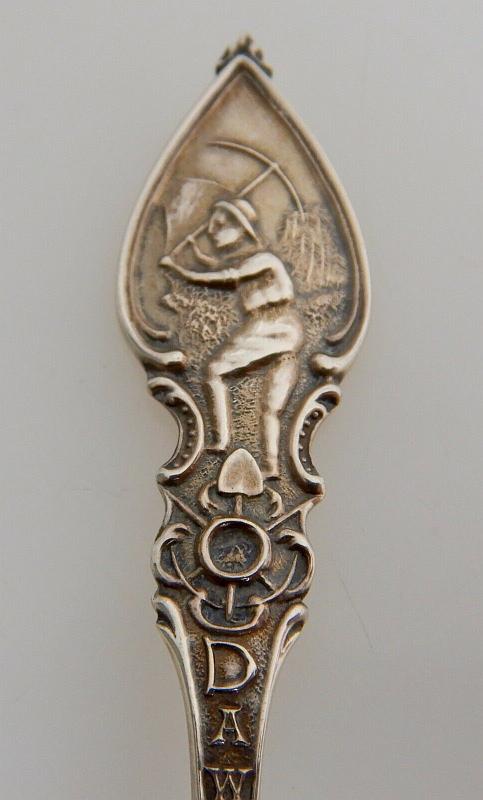 Souvenir Mining Spoon Handle Dawson City Yukon Canada.jpg - SOUVENIR MINING SPOON DAWSON CITY YUKON - Sterling silver demitasse spoon, 4 3/8 in. long, embossed miner figure panning for gold in bowl, handle marked DAWSON with a miner holding a pick at top, ca.1900, reverse with Sterling marking and maker’s mark of P. W. Ellis & Co. Toronto Canada (1877 -1928) later absorbed by Henry Birks & Sons of  Montreal in 1928, weight 12 gms. [When news first broke of gold being discovered in the Yukon, what became immortalized as the Klondike Gold Rush of 1896-99 kick started a mass influx of prospectors into the small northern town of Dawson City.  Founded in 1897, and fittingly named after noted Canadian geologist George M. Dawson, Dawson City became the heart of the Klondike Gold Rush and the capital of the Yukon, the center of activity for the thousands upon thousands of prospectors who flooded in each year. The hope of striking it rich was more than enough to stir the imaginations of an estimated 100,000 men and women who risked life and limb to make their fortune in the northern capital. Built up seemingly overnight, Dawson City was little more than a remote trade outpost at the dawn of the Gold Rush, with the first settlers forced to sleep in tents and under their own wagons. The town that became Dawson City grew exponentially over the next few years.  Constructed mainly out of wood, and where extra expense could be spared, capped in pressed tin, the town included false fronts and wooden sidewalks.  Before long, Dawson City had grown into a proper town, complete with hotels, saloons, banks, and more than one theatre. Faced with what by any route, either by land or sea, was sure to be a journey fraught with peril, thousands of fortune seekers made their way to the Klondike via the infamous Chilkoot Pass, an unforgiving mountain stretch that soon became synonymous with the Klondike Gold Rush. Often carrying more than 100 pounds of supplies on their backs, and outfitted in the extraordinarily inadequate winter clothes and hiking gear of the day, travelers were often forced back by the cold, or simply died along the way. The vast majority of those who made it to Dawson City would leave as ruined souls with not a penny, or nugget, to their name. By 1899, the Klondike Gold Rush was all but over, and the last stragglers and determined hopefuls abandoned Dawson City over the course of the next few years. The peak population of 40,000 in 1898 plummeted to well below 5,000 by 1902. Into the first half of the 20th century, Dawson's fortunes continued to slide. In 1953, Yukon’s official capital was moved to Whitehorse.]